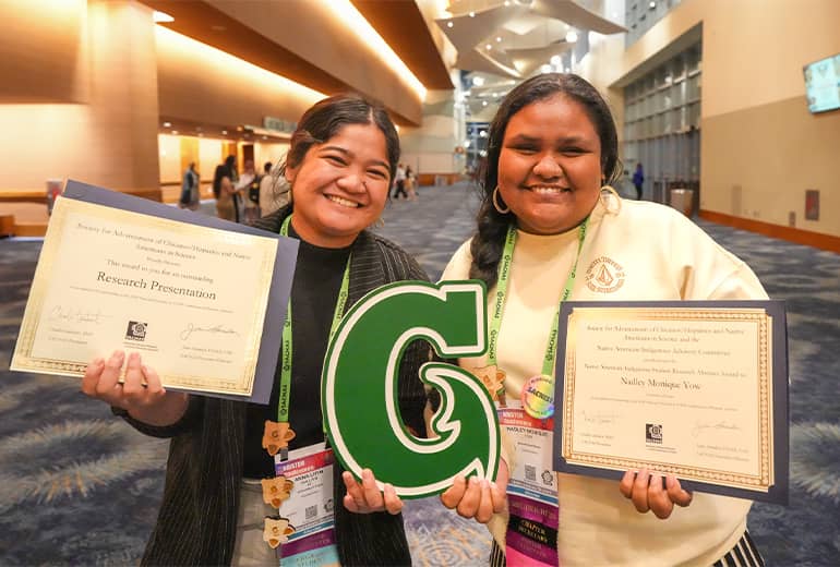 Two students pose for photo with Triton G and awards