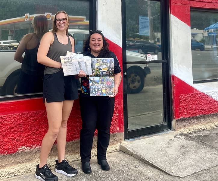 Davina Artero and G3 Kupu Corps Outreach and Extension Assistant pose with 2024 Guam Tide Chart Calendar