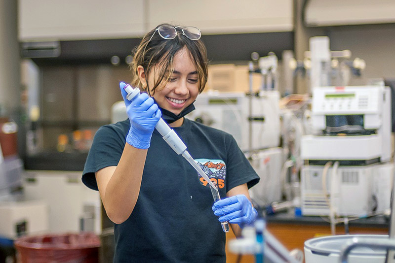 A photo of a student using a pipette in a lab