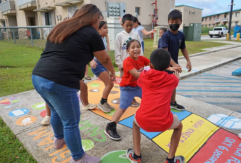 Teacher facilitates outdoor game that promotes activity and healthy eating as children play