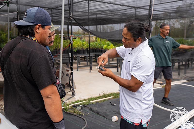 UOG Extension horiculturalist Joseph Tuquero instructs the buidling of a micro-irrigation system in the UOG CIS nursery. A man pointing to two pieces of PVC pipe