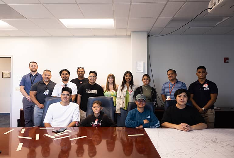 The fourth cohort of UOG drone corps pose for a photo in a nice office space