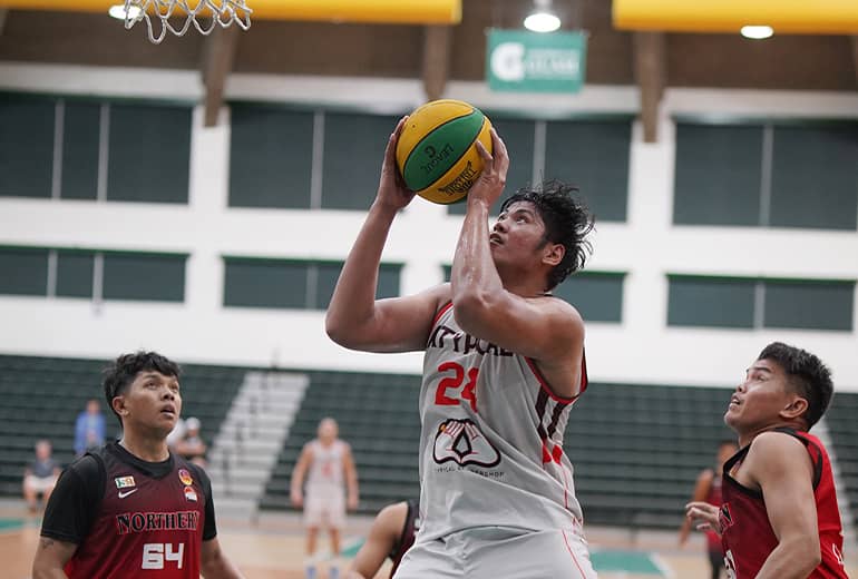 Athlete shoots basketball while flanking opponenents watch