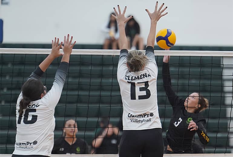 Two GuamPro1 volleyball players attempt to block spike from opposing team