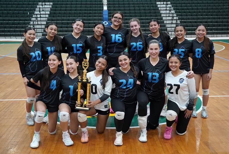 Volleyball team in back jerseys with blue numbers poses for group photo