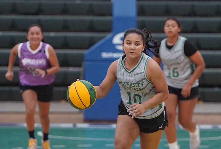 medium shot of #10 in gray jersey dribbling basketball while teammate and opposing team member follow behind