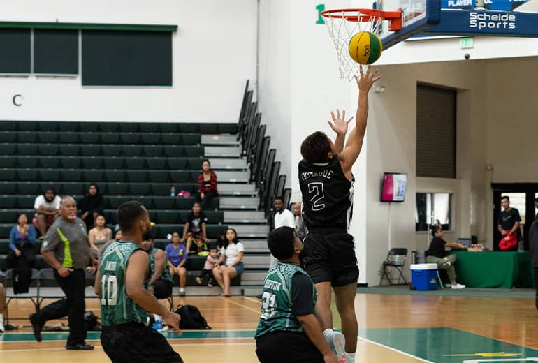 Athlete shoots ball in basket during Triton League game