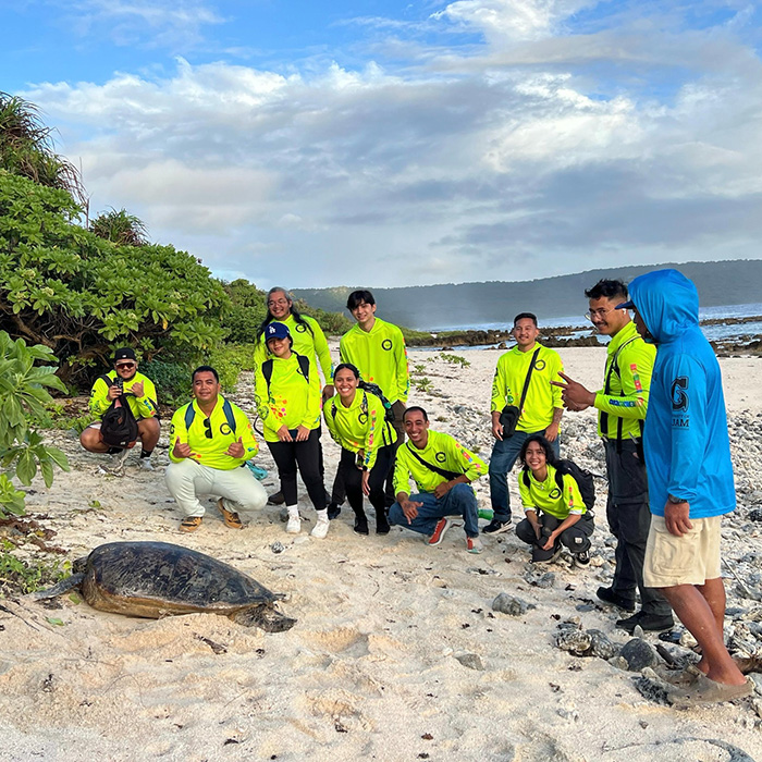 Conservation Corps members on the beach with a sea turtle