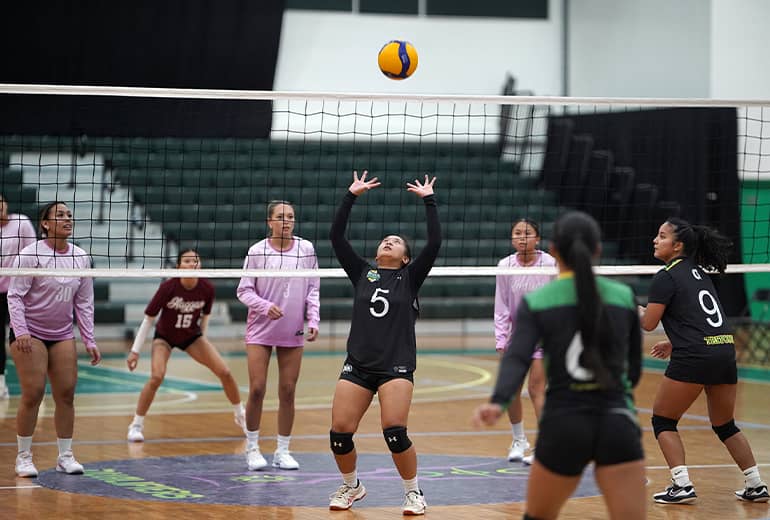 Player #5 in black sets volleyball for teammate