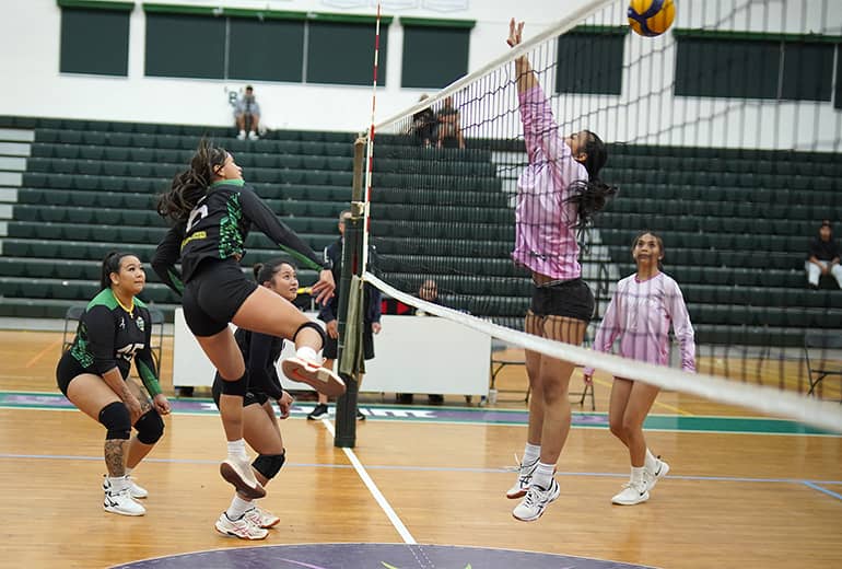Player in pink attempts to block opponent spike
