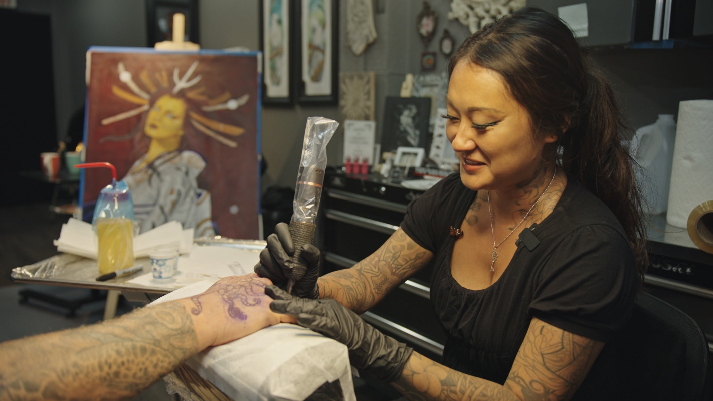 Woman giving a tattoo on someone arm